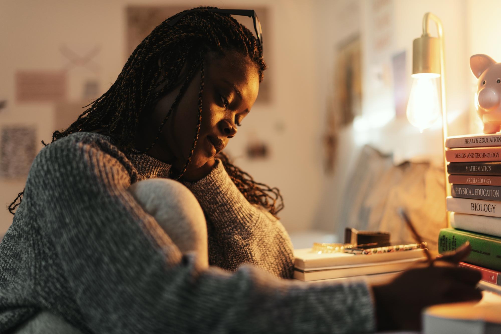 A person sitting quietly in a dim, warm corner.