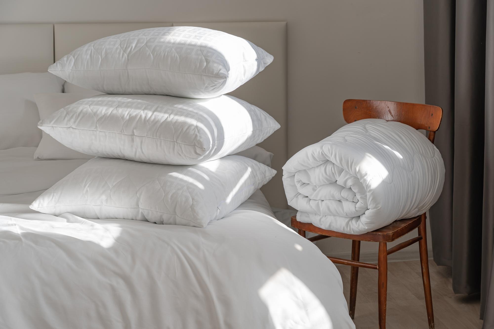 Close-up of a neatly made bed with supportive pillows and soft linen in warm neutral tones