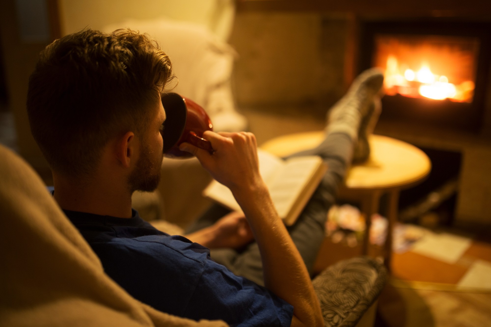 Cozy evening living room warm lamp person relaxing in chair.