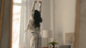 Person doing a calm morning routine stretching near a bright window