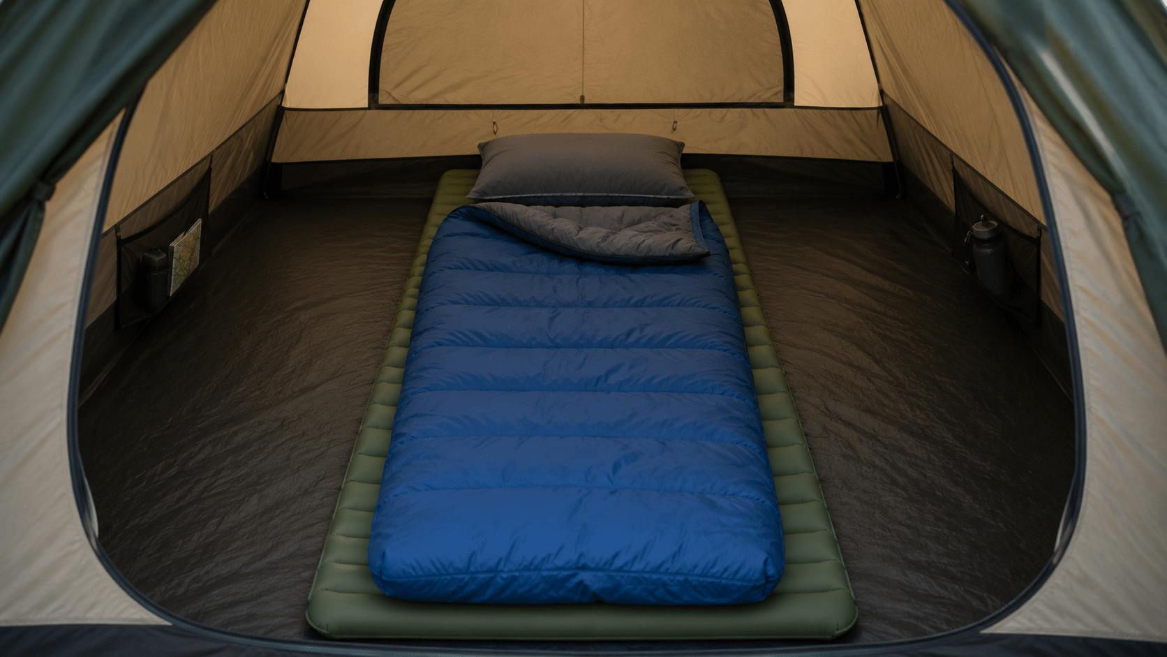 Sleeping pad, sleeping bag, and pillow laid out neatly inside a tent