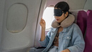 passenger by the airplane window with a neck pillow and eye mask