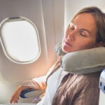traveler comfortably asleep, head supported by a neck pillow