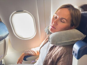 traveler comfortably asleep, head supported by a neck pillow