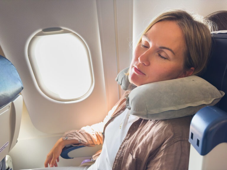 traveler comfortably asleep, head supported by a neck pillow