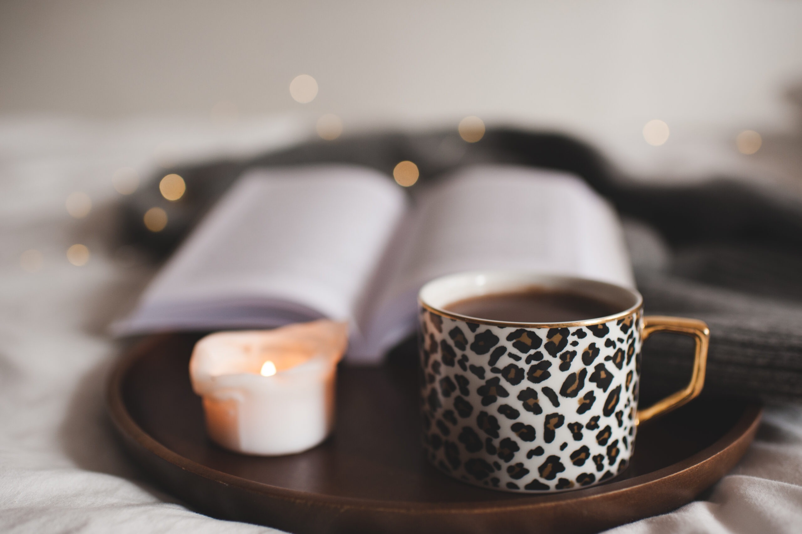 Cozy bedside table with a warm cup of herbal tea, a book, and a small candle casting soft light