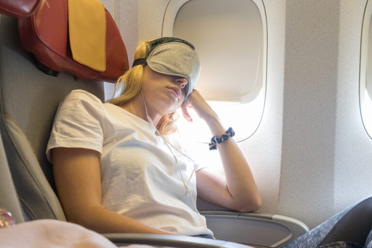 woman sleeping on airplane with eye mask